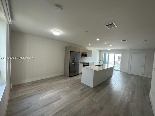 A modern kitchen features stainless steel appliances, a central island, and light wood-look flooring — 2561 NE 193rd St # 1208, Miami FL 33180, MIAMI, FL