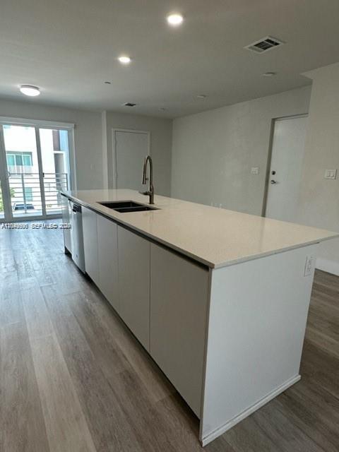 A modern kitchen features a white island with a sink and light wood-look flooring — 2561 NE 193rd St # 1208, Miami FL 33180, MIAMI, FL