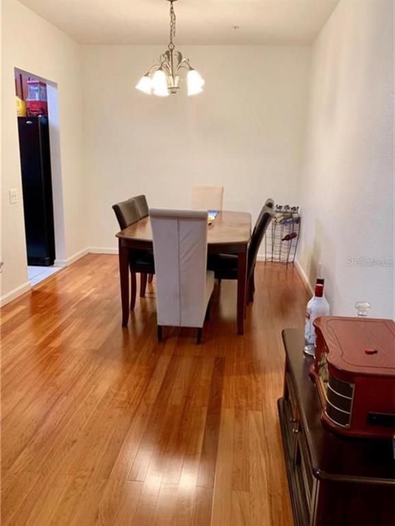 A dining room with a wooden table, upholstered chairs, a chandelier, and hardwood flooring — 2576 SAN TECLA STREET UNIT 107, ORLANDO, FL