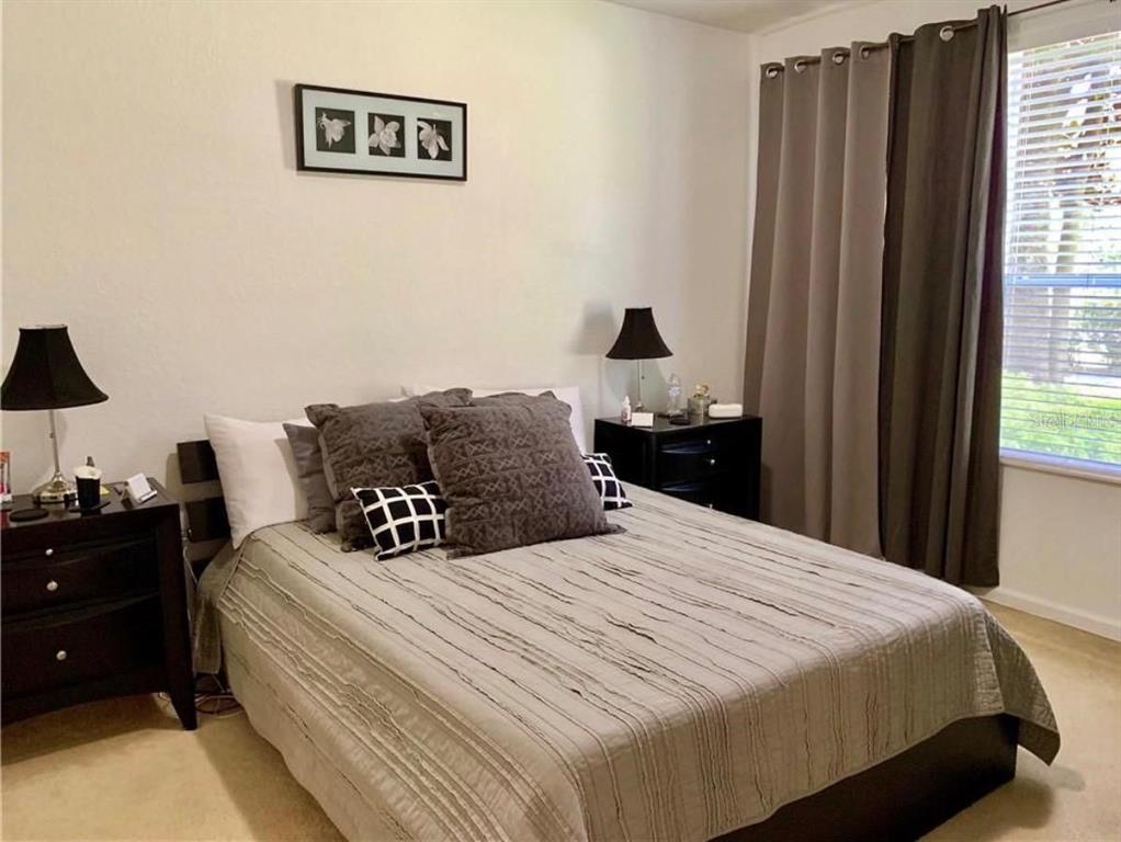 A bedroom features a bed with a textured gray comforter, two nightstands, and wall art — 2576 SAN TECLA STREET UNIT 107, ORLANDO, FL