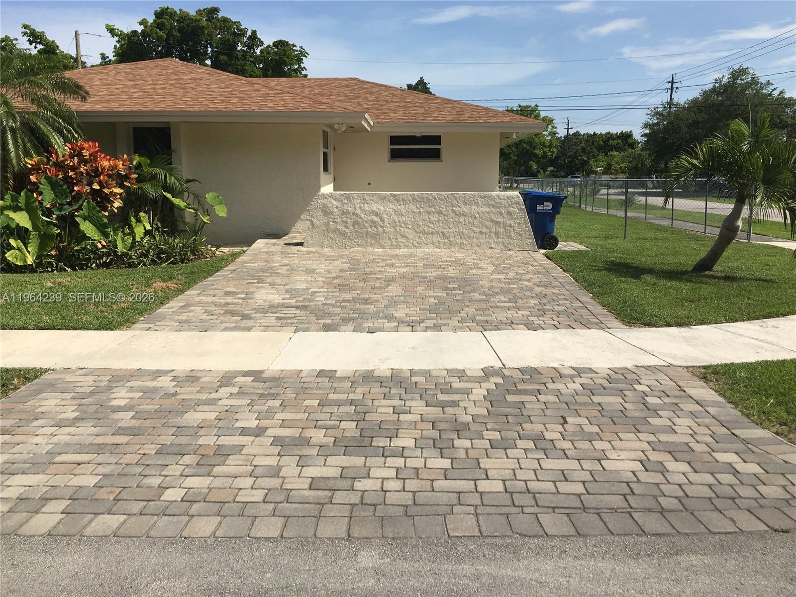 A paved driveway leads to a house with a low white wall and landscaping — 5782 SW 61st St # 5782, Miami FL 33143, MIAMI, FL
