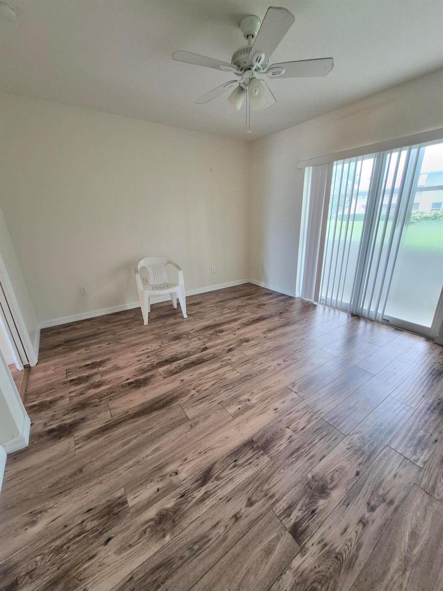 An empty room with wood-look flooring, a ceiling fan, and sliding glass doors — 27 Easthampton B, West Palm Beach FL 33417, WEST PALM BEACH, FL