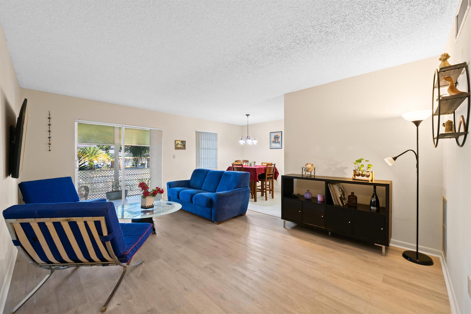 A living room with blue furniture, light wood flooring, and an adjacent dining area — 5180 E Sabal Palm Boulevard # 239, Tamarac FL 33319, TAMARAC, FL
