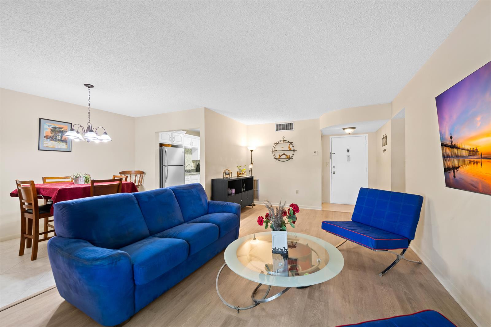 A living room with a blue sofa, a glass coffee table, and a dining area — 5180 E Sabal Palm Boulevard # 239, Tamarac FL 33319, TAMARAC, FL