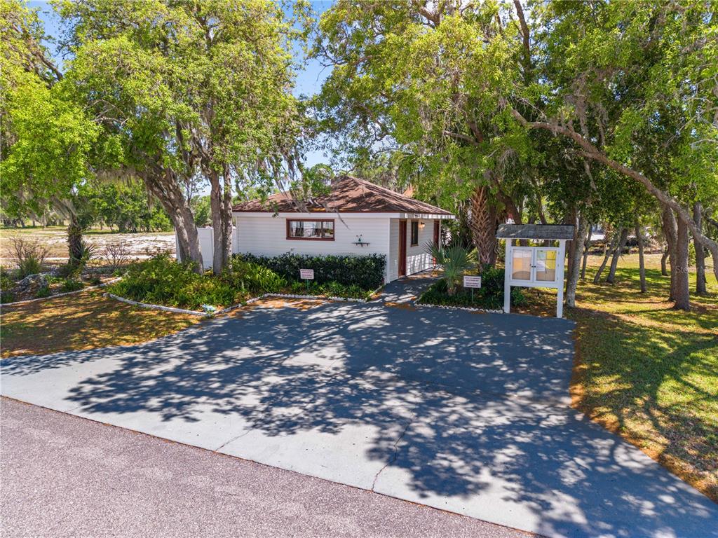 A small white building with a brown roof sits behind a paved driveway under trees — 34 FAIRVIEW DRIVE N, HAINES CITY, FL