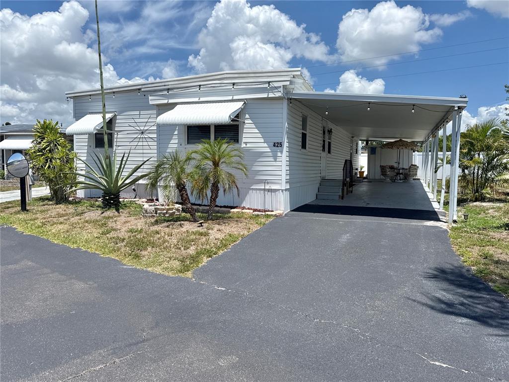 A white mobile home features a carport, a paved driveway, and small palm trees — 425 MOUNT PINEY AVENUE NE UNIT 681, ST PETERSBURG, FL