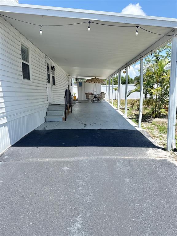 A covered carport with a concrete floor extends alongside a white-sided mobile home — 425 MOUNT PINEY AVENUE NE UNIT 681, ST PETERSBURG, FL