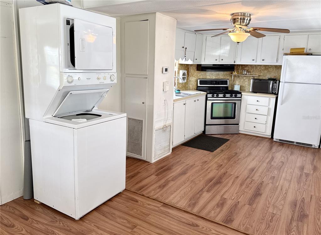 A kitchen features white cabinets, stainless steel appliances, and a stacked washer and dryer unit — 425 MOUNT PINEY AVENUE NE UNIT 681, ST PETERSBURG, FL