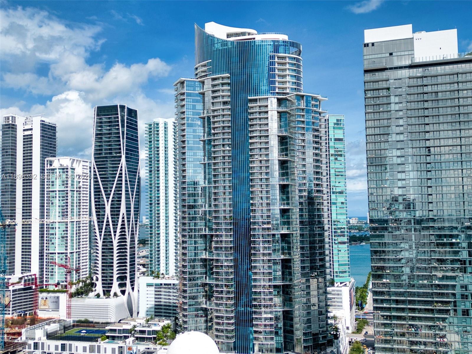 A high-angle view of several modern glass skyscrapers in a dense urban waterfront setting — 851 NE 1st Ave # 4107, Miami FL 33132, MIAMI, FL