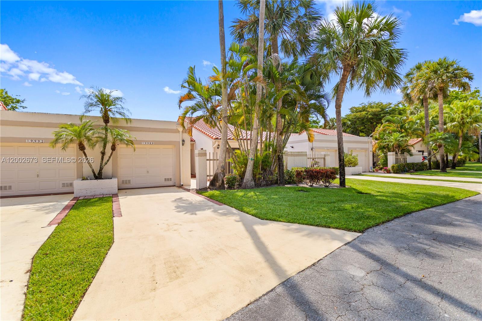 A single-story residential building features a concrete driveway, a garage, and palm trees — 19988 Rima Cir, Boca Raton FL 33434, BOCA RATON, FL