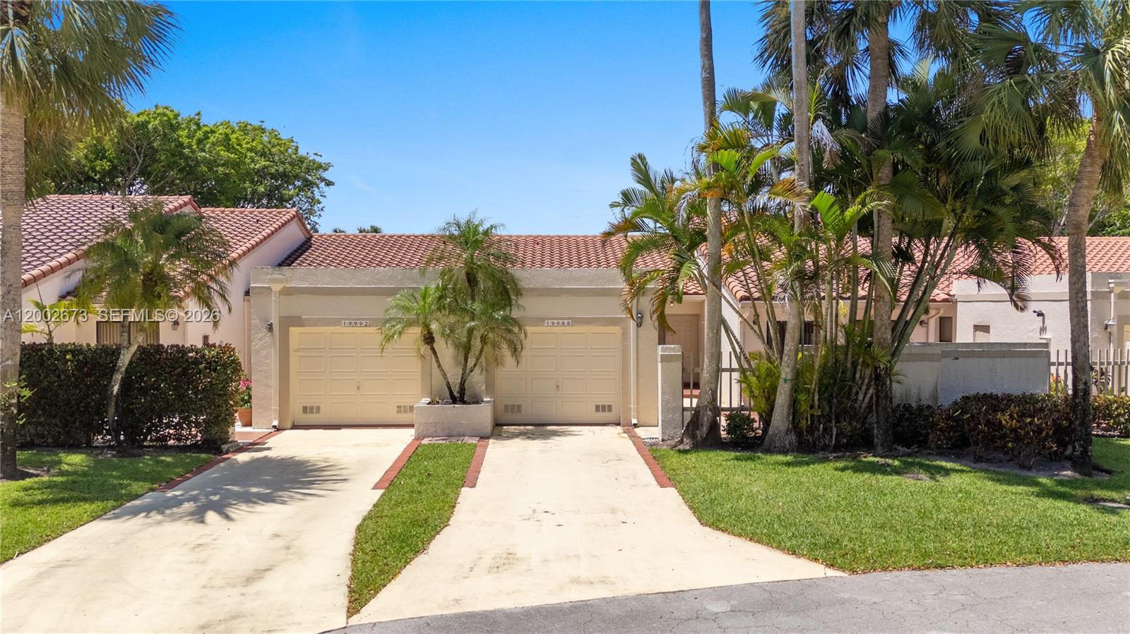 A single-story duplex with two beige garage doors and a red tile roof — 19988 Rima Cir, Boca Raton FL 33434, BOCA RATON, FL