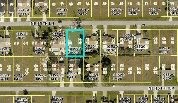This is an aerial map showing a vacant residential lot highlighted in blue — 1934 NE 15TH LANE, CAPE CORAL, FL