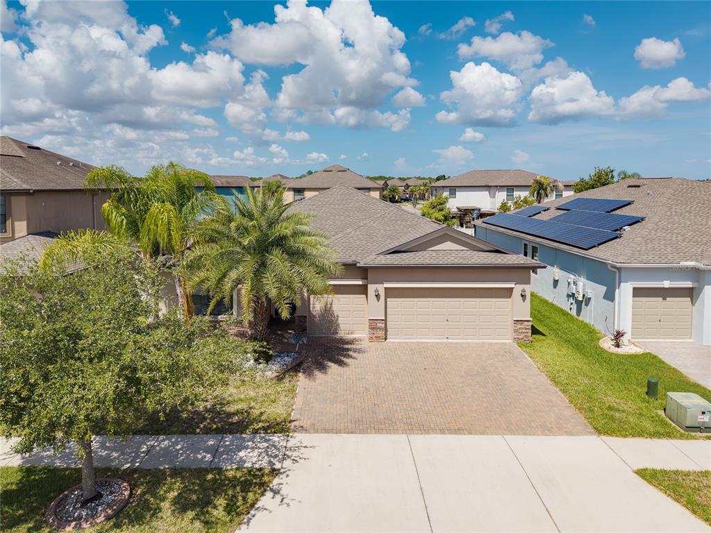 An aerial view of a suburban house with a paved driveway, garage, and solar panels — 10009 CELTIC ASH DRIVE, RUSKIN, FL