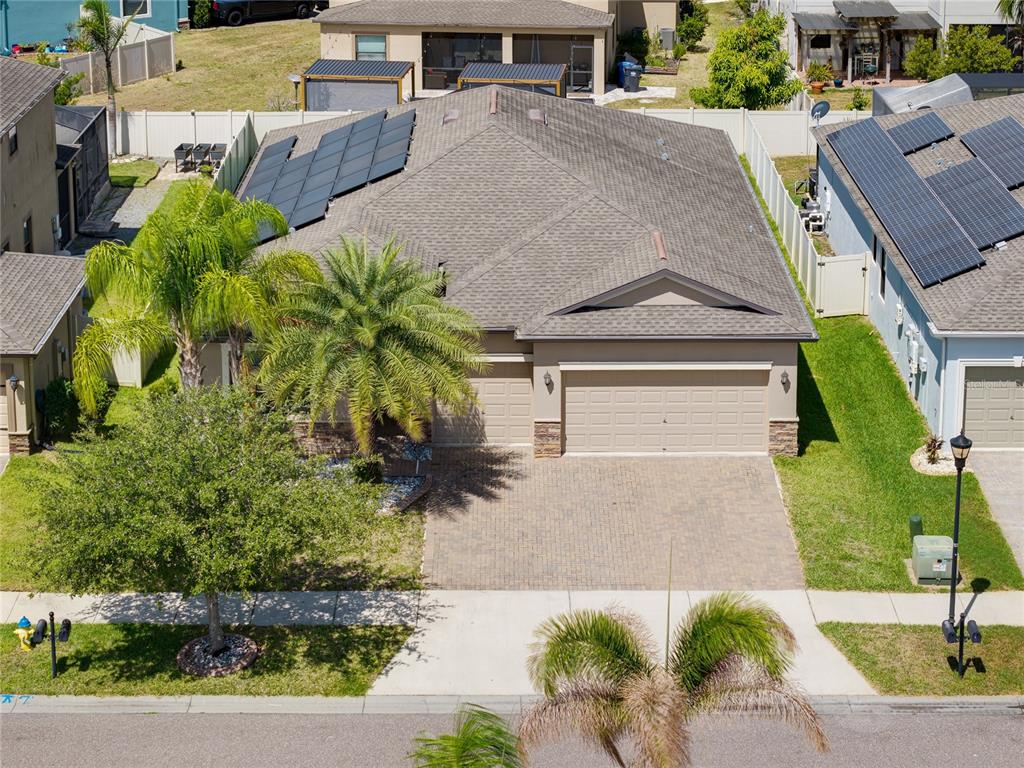 An aerial view of a suburban house with a paved driveway and solar roof panels — 10009 CELTIC ASH DRIVE, RUSKIN, FL