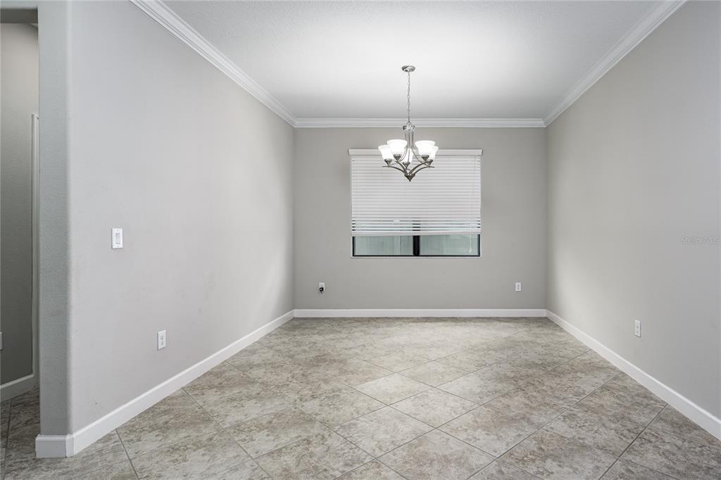 An empty dining room with light gray walls, tile flooring, and a central chandelier — 10009 CELTIC ASH DRIVE, RUSKIN, FL