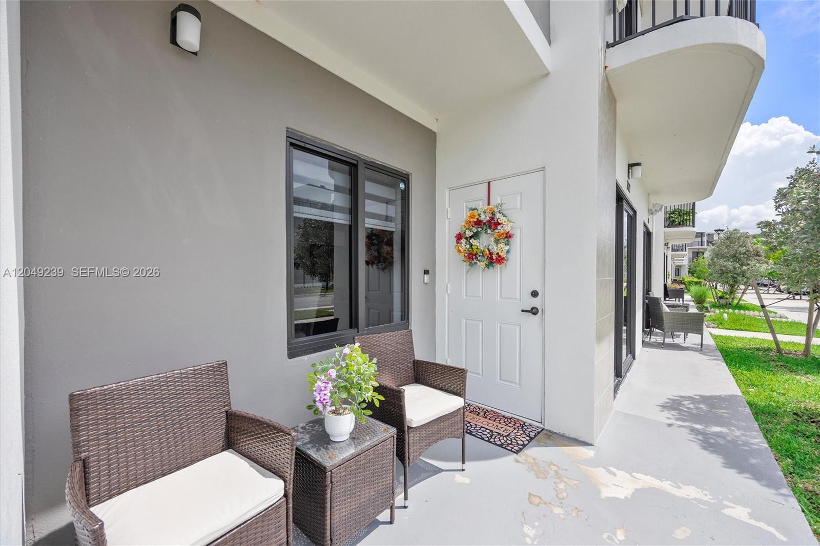 A patio features two wicker chairs, a small table with a plant, and a door — 26122 SW 146th Ave, Homestead FL 33032, HOMESTEAD, FL