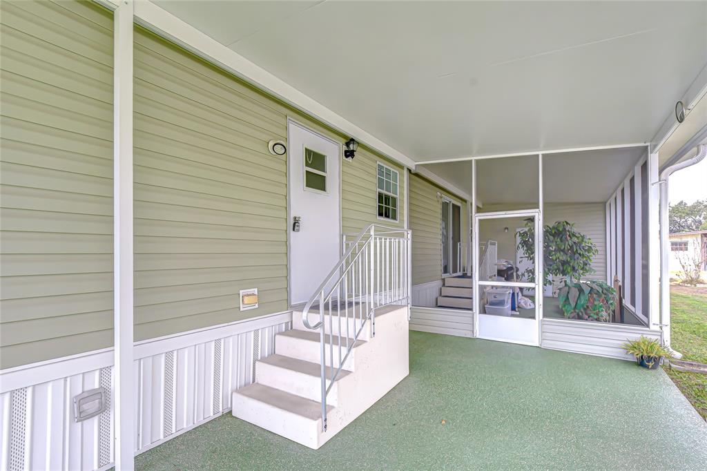 A covered porch with green flooring, a white staircase, and a screened-in enclosure — 3337 DAWNS DELL, ZEPHYRHILLS, FL