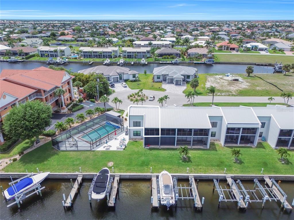 An aerial view shows a waterfront building with a pool, boat docks, and canal — 1318 WESLEY DRIVE UNIT 124B, PUNTA GORDA, FL