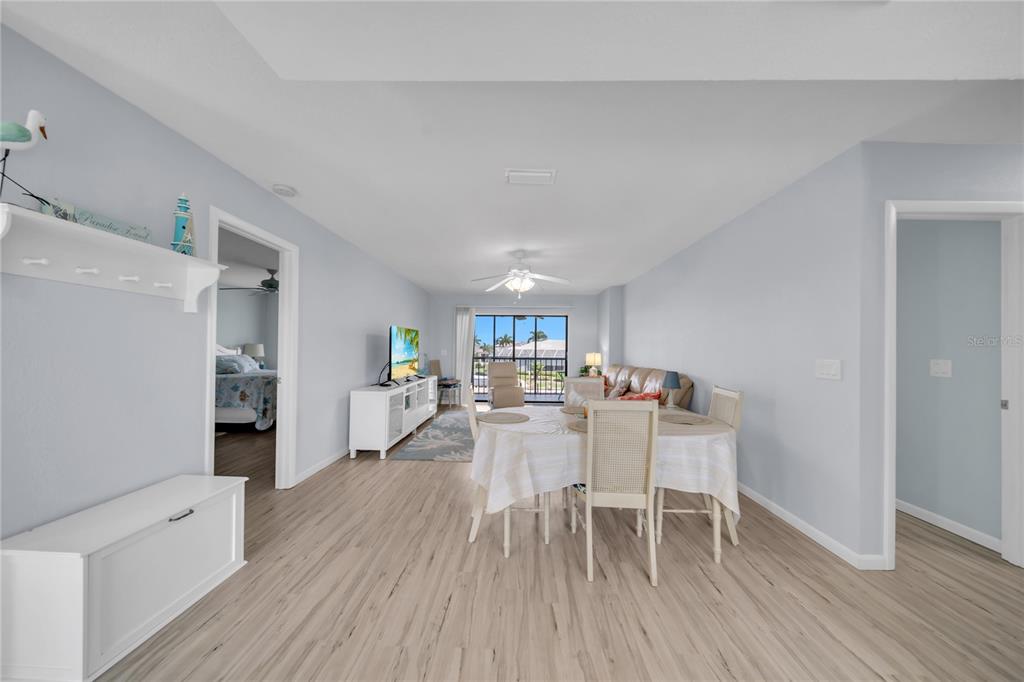 A living and dining area features light wood-look flooring, pale blue walls, and a balcony view — 1318 WESLEY DRIVE UNIT 124B, PUNTA GORDA, FL