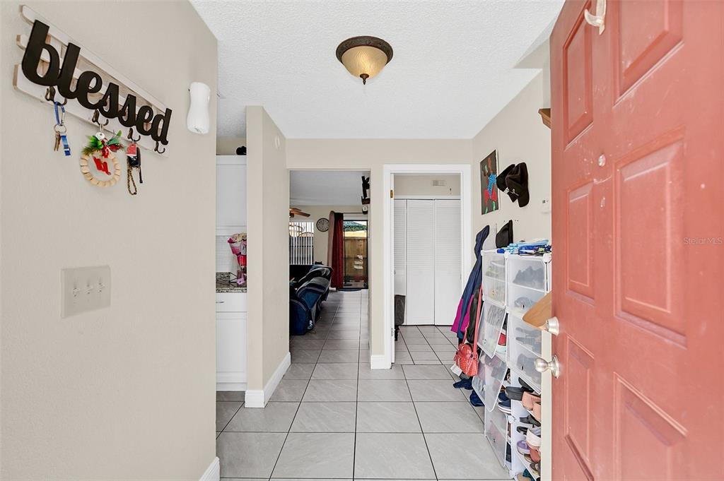 An entryway with tile flooring leads to a living area with a red front door — 1612 SANDY POINT SQUARE UNIT 56, ORLANDO, FL