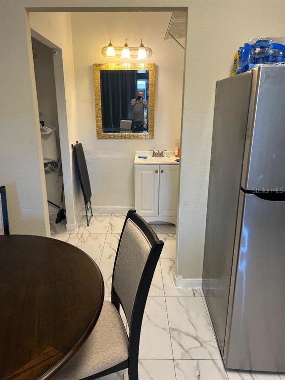 A dining area with a round table leads to a bathroom vanity and a refrigerator — 8421 S ORANGE BLOSSOM TRAIL UNIT 248, ORLANDO, FL
