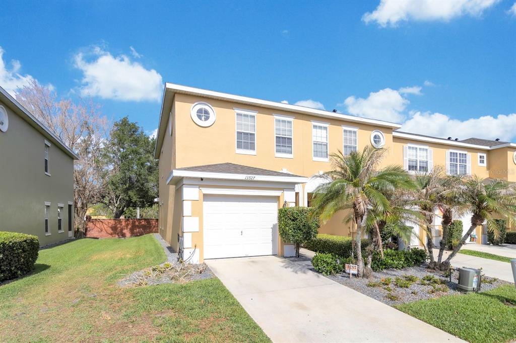 A two-story tan townhouse features a single-car garage and a small front lawn — 13527 DANIELS LANDING CIRCLE, WINTER GARDEN, FL