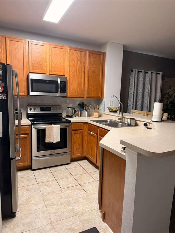 A kitchen features wood cabinets, stainless steel appliances, and a tiled floor — 13527 DANIELS LANDING CIRCLE, WINTER GARDEN, FL