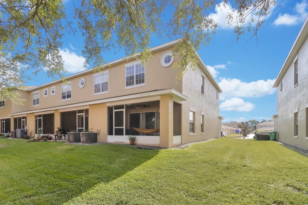 The exterior rear view of a two-story tan townhouse with a screened-in patio — 13527 DANIELS LANDING CIRCLE, WINTER GARDEN, FL