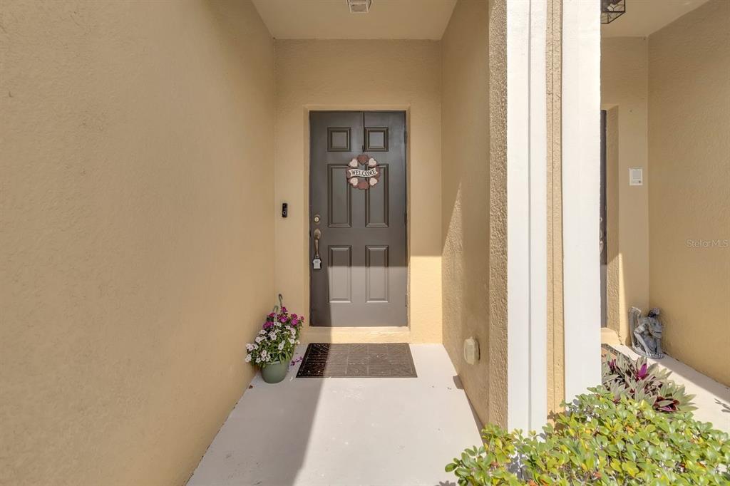 A covered entryway features a dark gray front door with a heart-shaped welcome sign — 13527 DANIELS LANDING CIRCLE, WINTER GARDEN, FL