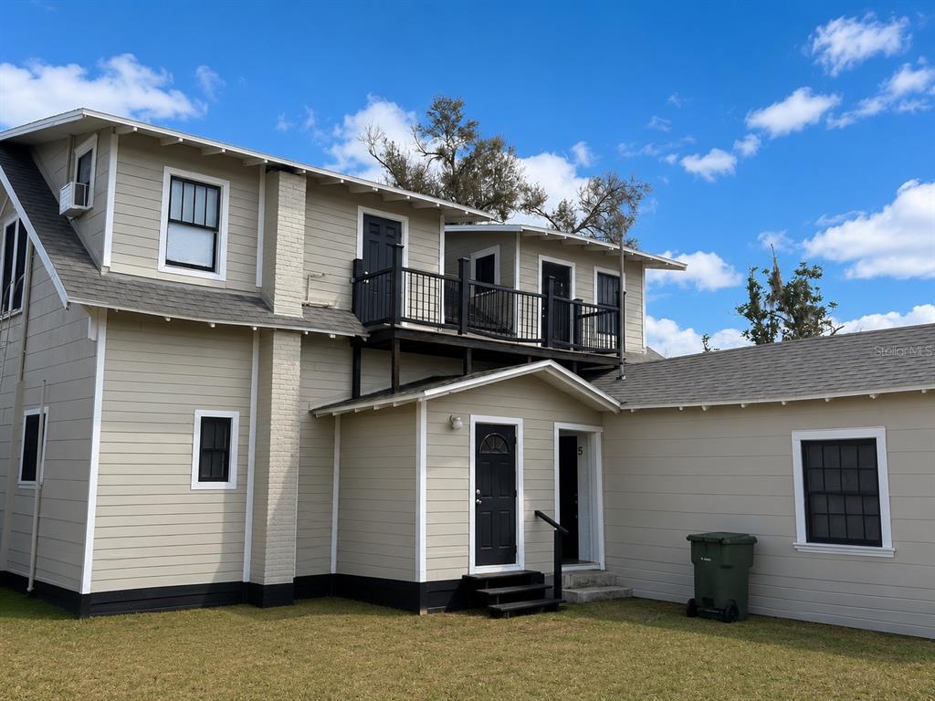 A two-story house with beige siding, black trim, and an upper-level balcony — 1339 7TH STREET SW, WINTER HAVEN, FL