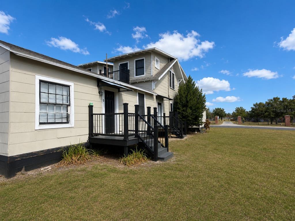A two-story light-colored building with black railings and stairs sits on a grassy lot — 1339 7TH STREET SW, WINTER HAVEN, FL