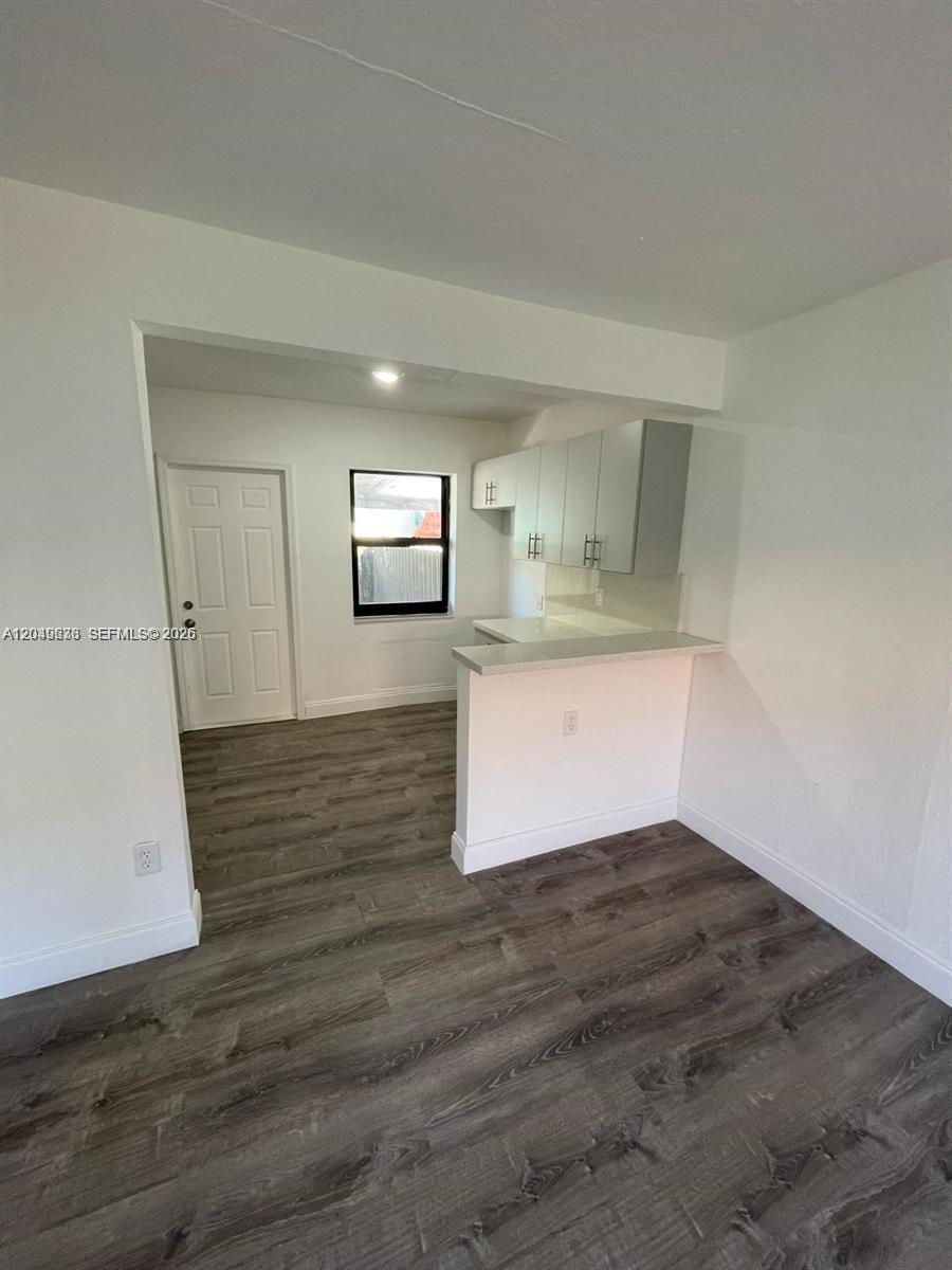 A small kitchen area features white cabinets, a breakfast bar, and wood-look flooring — 7360 SW 21st St # 7360, Miami FL 33155, MIAMI, FL