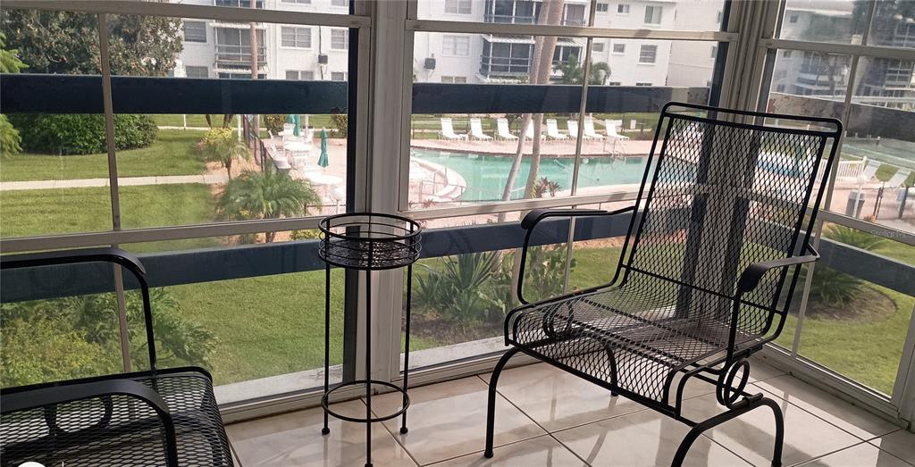 A screened-in porch features tile flooring, metal furniture, and a view of a swimming pool — 1875 SUNNY DRIVE UNIT G32, BRADENTON, FL