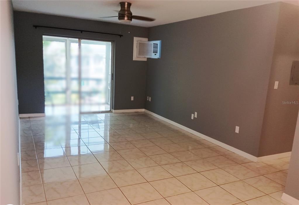 An empty room features gray walls, light-colored tile flooring, a ceiling fan, and sliding glass doors — 1875 SUNNY DRIVE UNIT G32, BRADENTON, FL