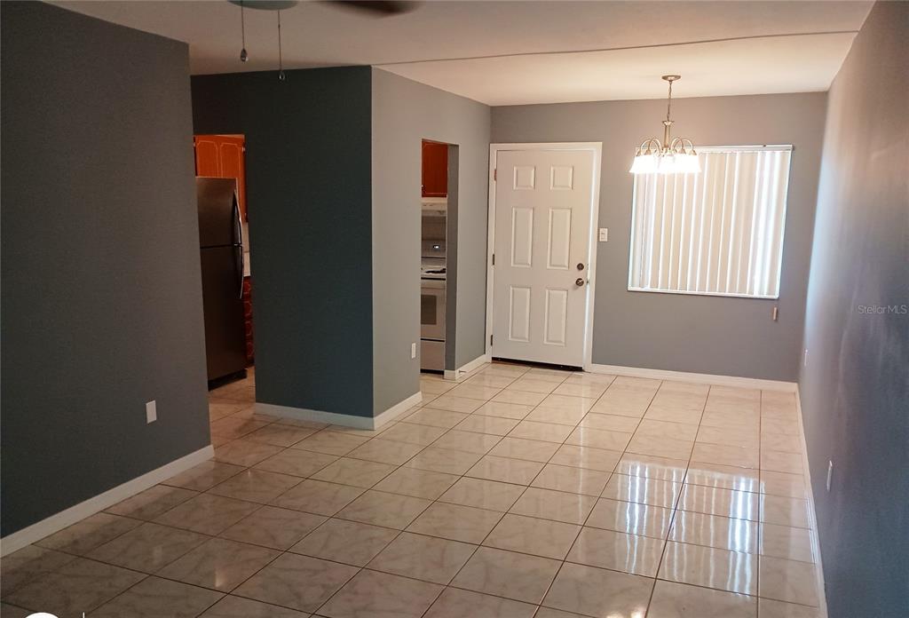 A dining area with tiled floors, a white door, and a hanging light fixture — 1875 SUNNY DRIVE UNIT G32, BRADENTON, FL