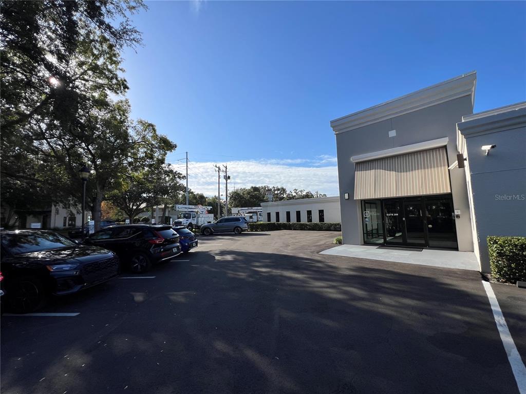 An exterior view of a commercial building entrance with a parking lot and trees — 3410 HENDERSON BOULEVARD, TAMPA, FL