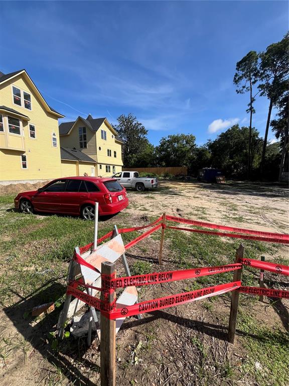 A red station wagon is parked on a dirt lot next to a yellow house — 262 NW 12TH AVENUE, GAINESVILLE, FL