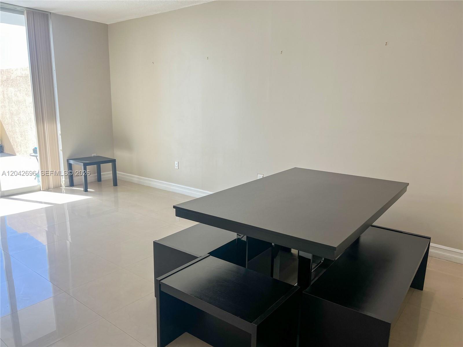 A dining area features a dark table with matching benches and light tile flooring — 117 NW 42nd Ave # 506, Miami FL 33126, MIAMI, FL