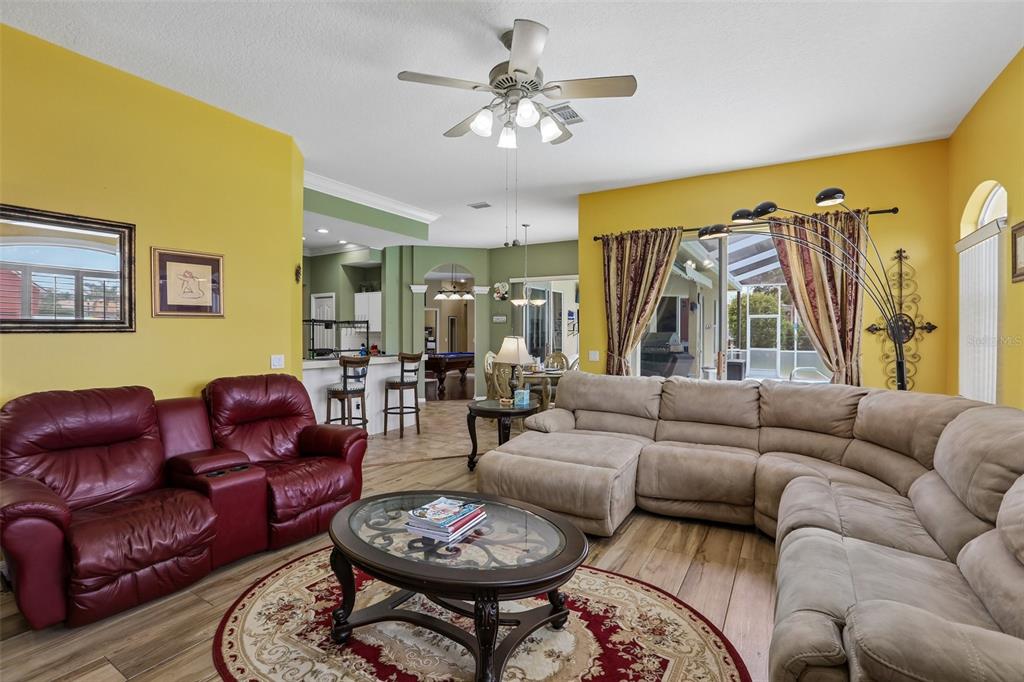 A living room with yellow walls, a red leather sofa, and a large beige sectional — 3542 CONIFER LOOP, SPRING HILL, FL