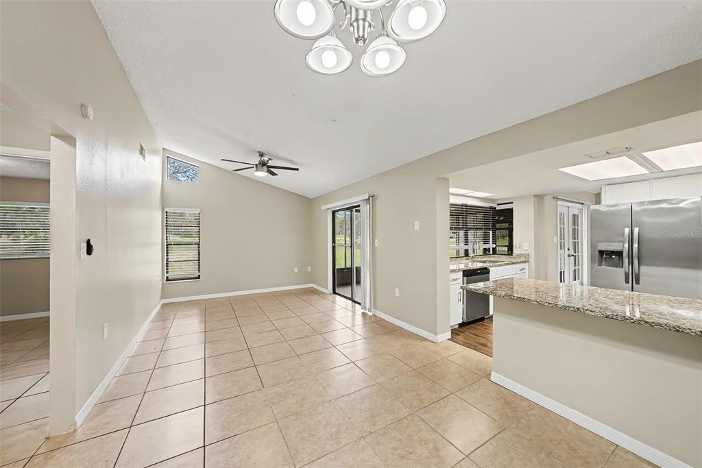 An open-concept dining area with tile floors, a vaulted ceiling, and an adjacent kitchen — 8009 PAGODA DRIVE, SPRING HILL, FL