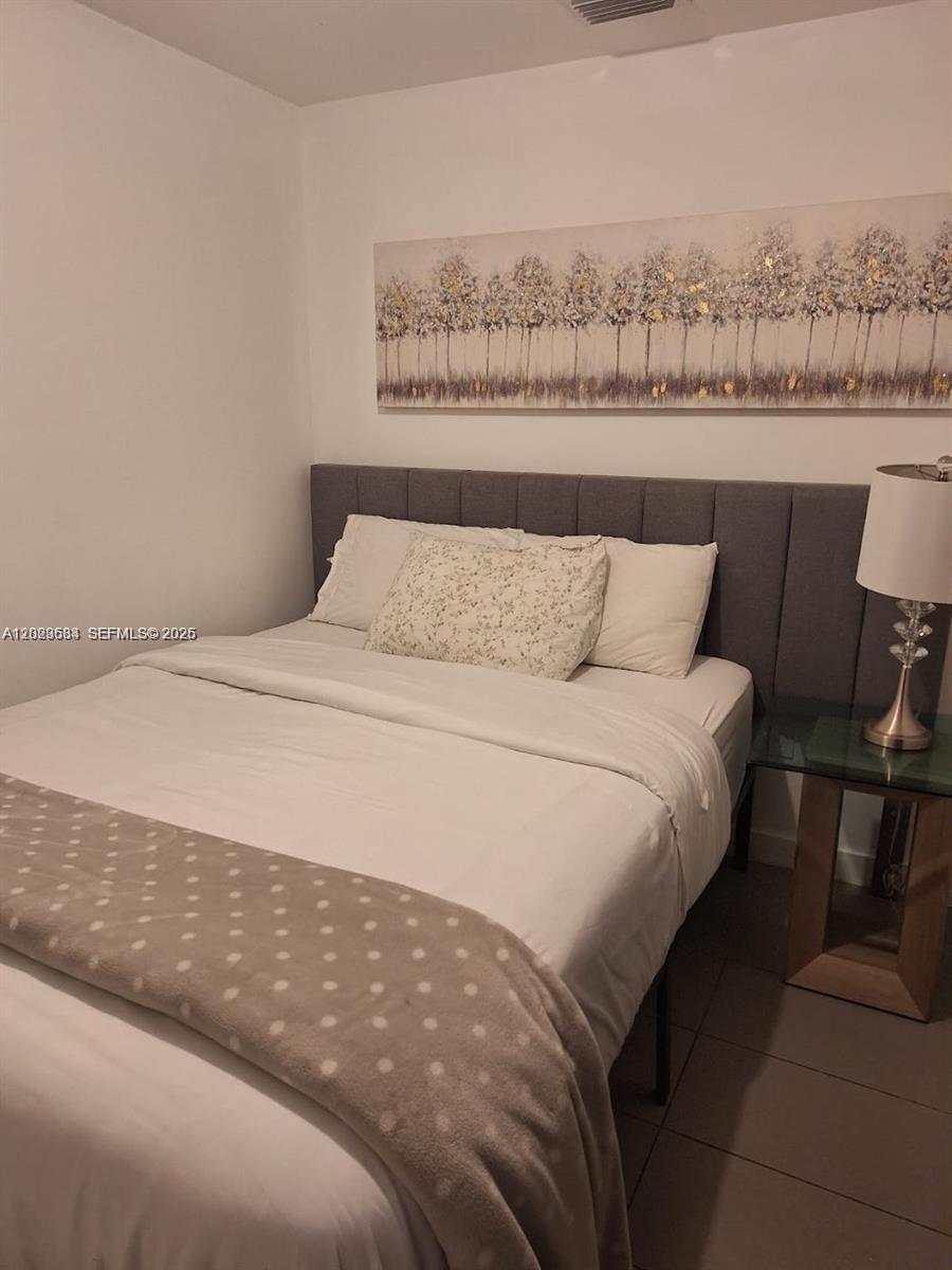 A bedroom features a gray upholstered headboard, a white bed, and a tree-themed wall painting — 1600 NE 1st Ave # 1612, Miami FL 33132, MIAMI, FL