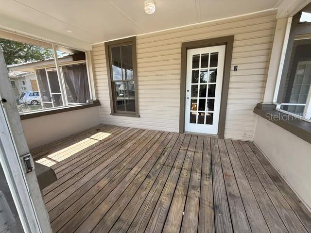 A covered wooden porch features a white-framed glass door and a large window — 510 E ORANGE AVENUE, EUSTIS, FL