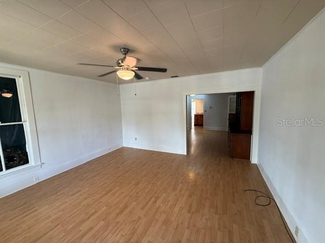 A living room features light wood-look flooring, a ceiling fan, and a doorway to another room — 510 E ORANGE AVENUE, EUSTIS, FL