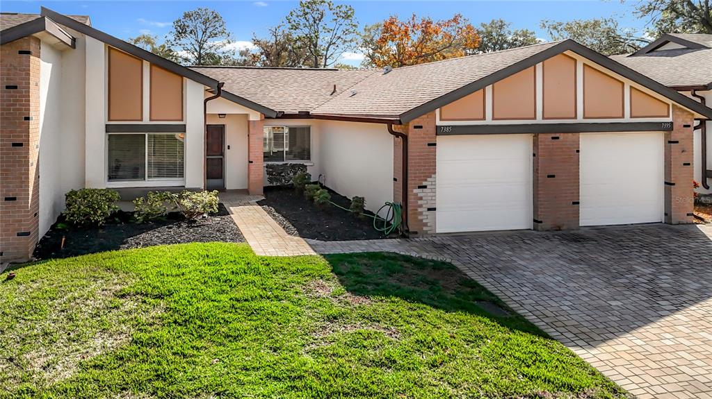 A single-story house with a brick facade, two garage doors, and a paved walkway — 7385 CRESTWOOD DRIVE, WEEKI WACHEE, FL