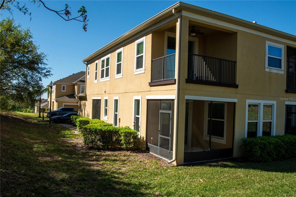The exterior of a two-story tan stucco townhouse features a screened-in patio and balcony — 17459 CHATEAU PINE WAY, CLERMONT, FL