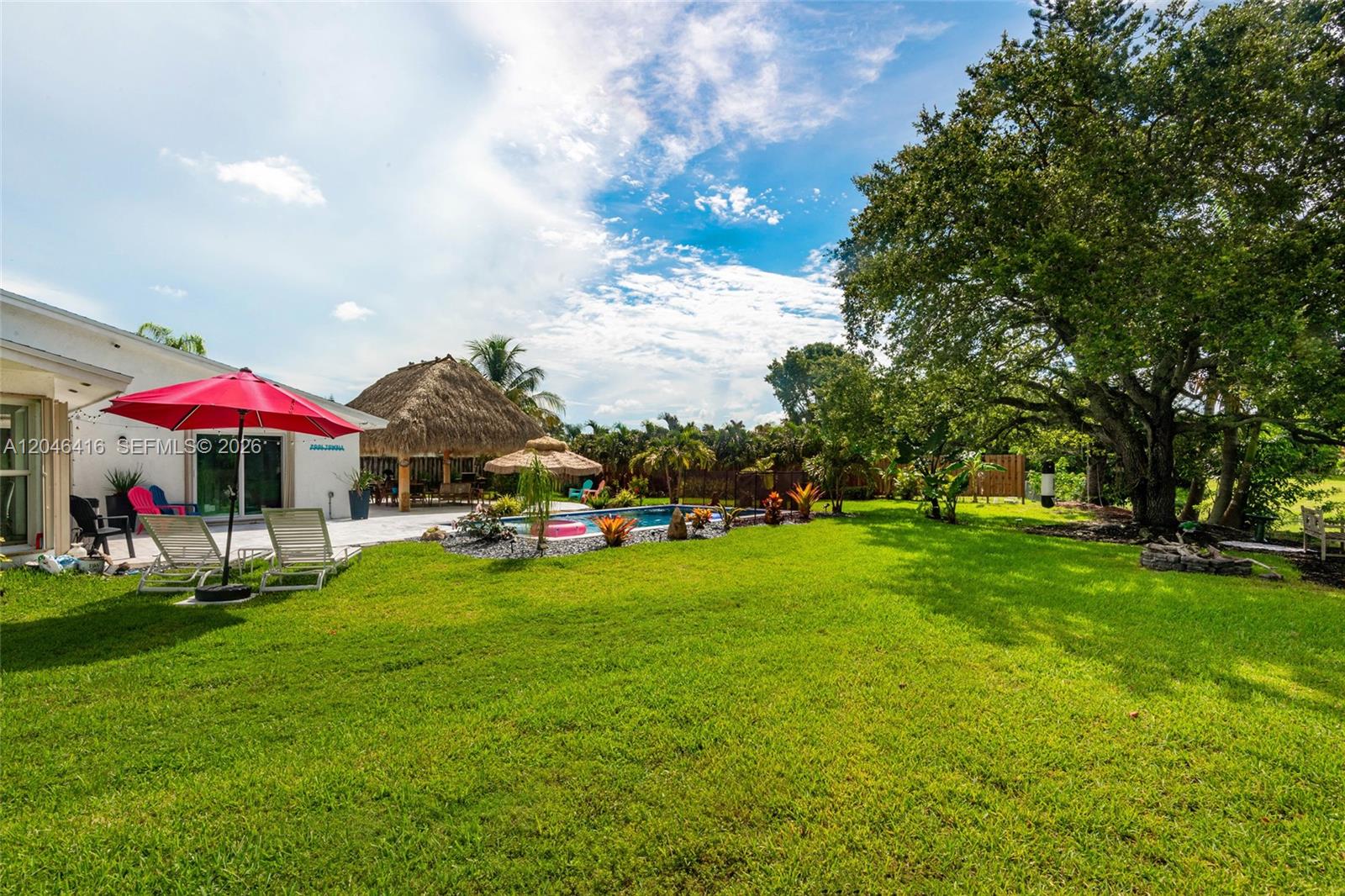 A backyard features a swimming pool, a thatched-roof tiki hut, and a red patio umbrella — 16736 SW 5th Way, Weston FL 33326, WESTON, FL