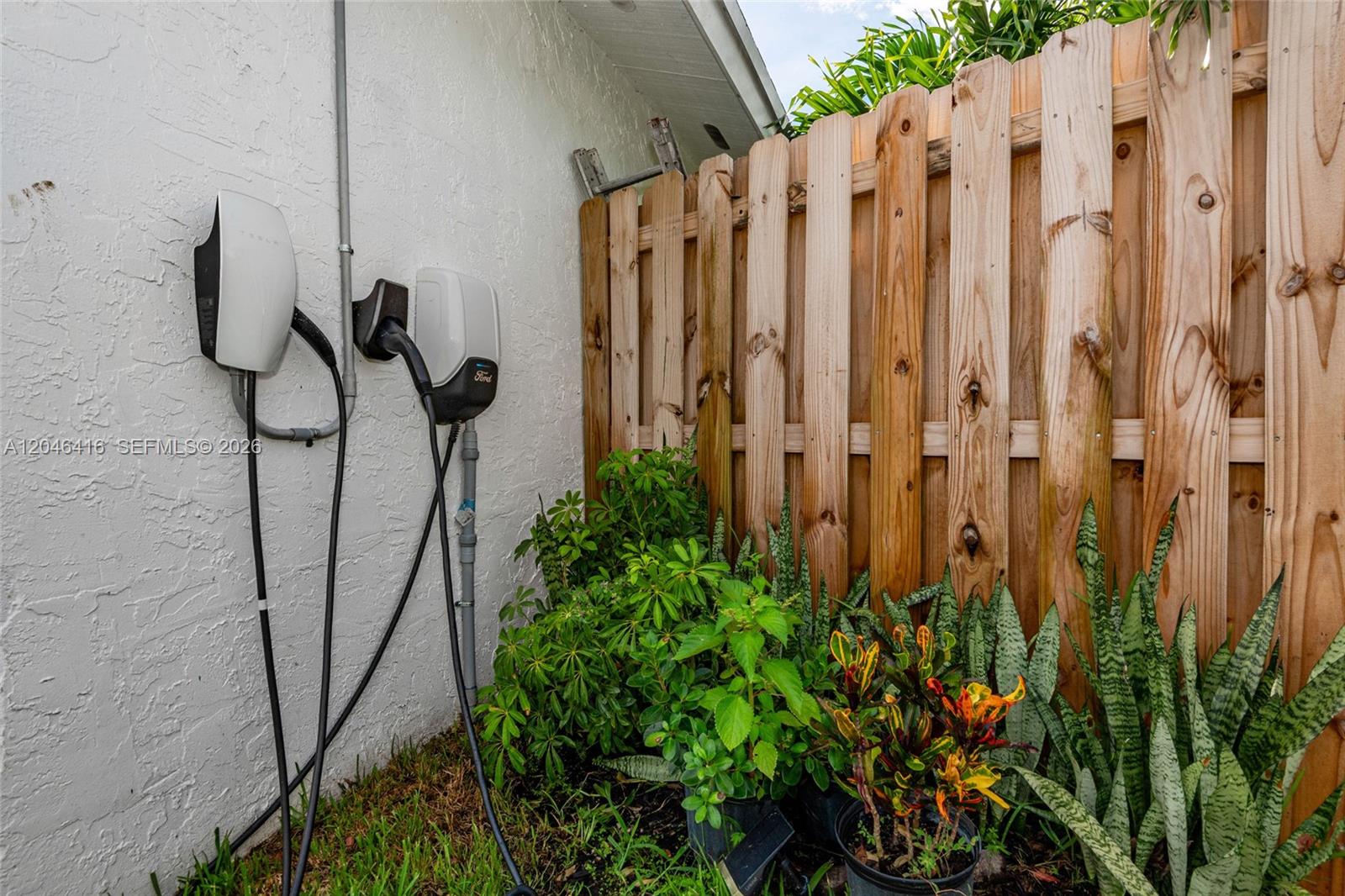Two electric vehicle charging stations are mounted on an exterior wall next to a wooden fence — 16736 SW 5th Way, Weston FL 33326, WESTON, FL
