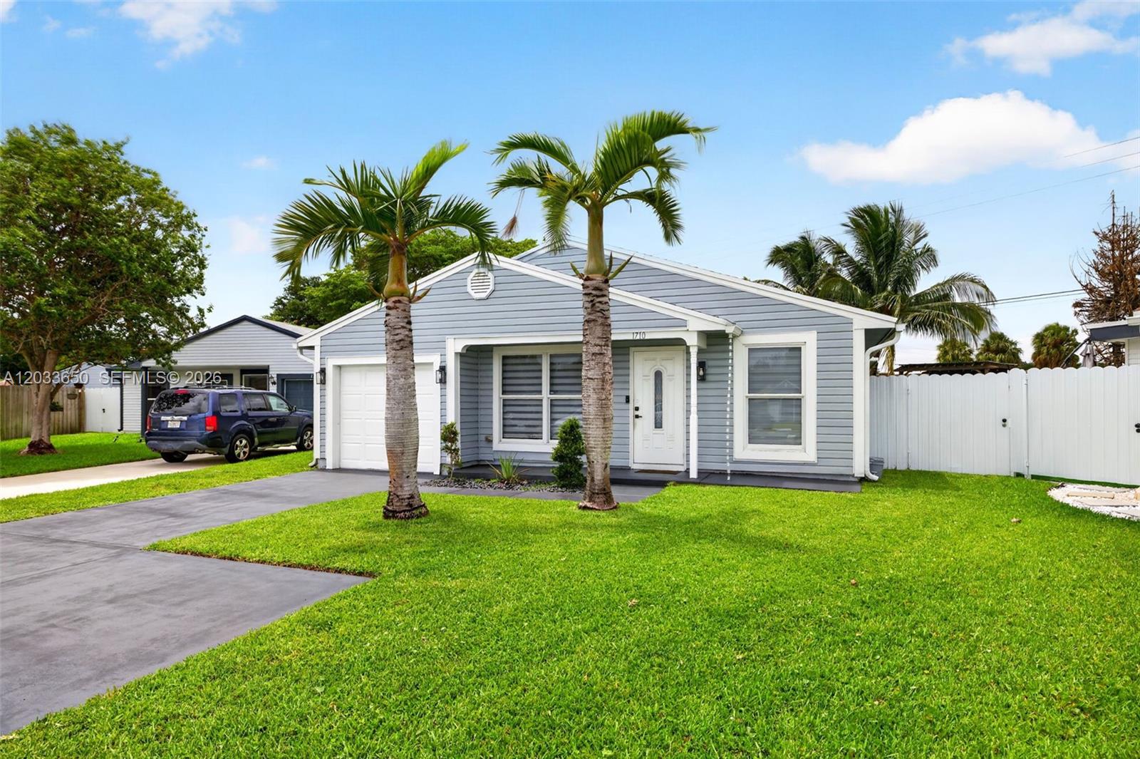 A light blue, single-story house with a white garage door and two palm trees — 1710 SW 83rd Ter, Miramar FL 33025, MIRAMAR, FL