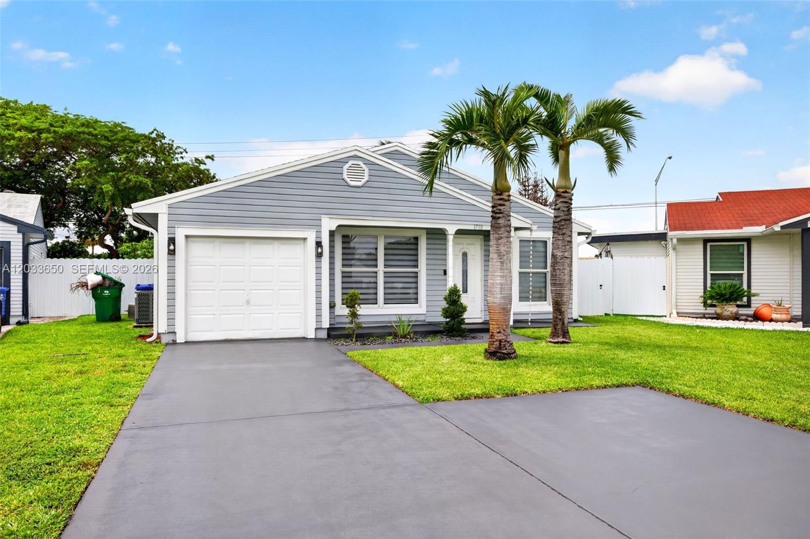A single-story house with gray siding, a white garage door, and two palm trees — 1710 SW 83rd Ter, Miramar FL 33025, MIRAMAR, FL