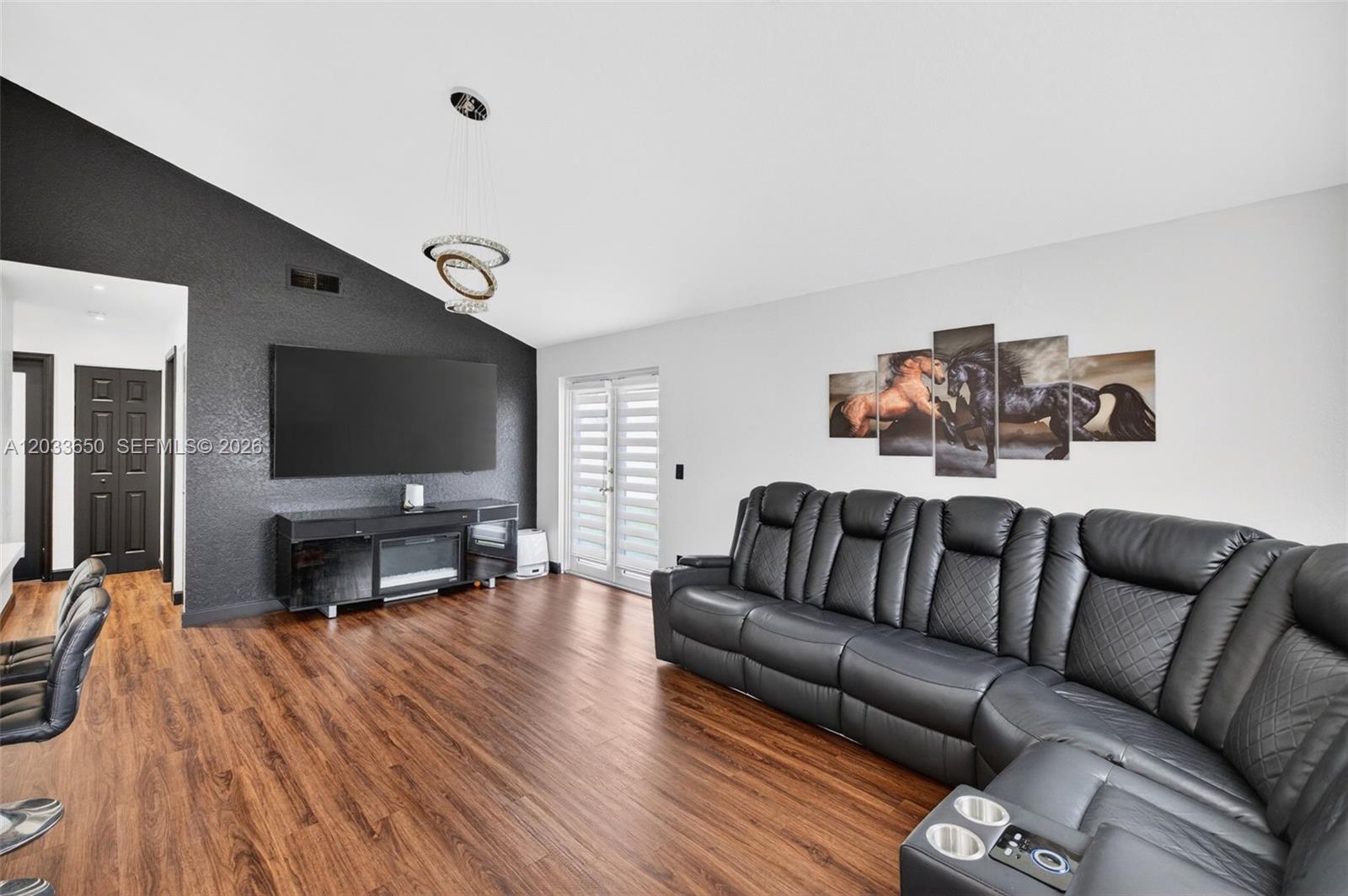 A living room features a black accent wall, a large television, and a leather sectional — 1710 SW 83rd Ter, Miramar FL 33025, MIRAMAR, FL